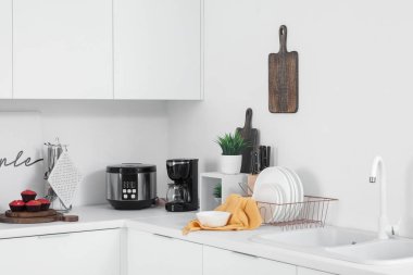 Kahve makinesi, çoklu fırın ve çatal bıçaklı beyaz mutfak tezgahları.