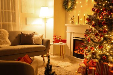 İçinde şömine, gri kanepe ve Noel ağacı olan şenlikli bir oturma odası.