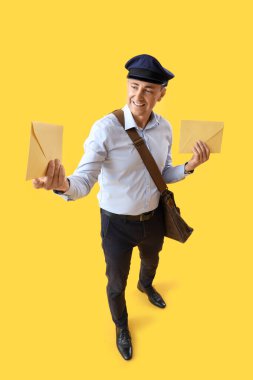 Sarı arka planda zarfları olan olgun bir postacı.