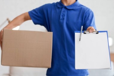 Odasında paket ve pano olan genç kurye, yakın plan.