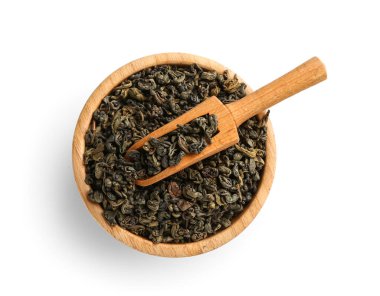 Kepçeli ahşap kase ve beyaz arka planda kuru yeşil çay yaprakları.