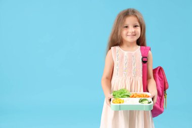 Sırt çantası ve mavi arka planda beslenme çantası olan mutlu küçük kız.