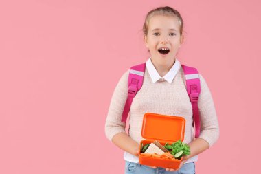 Şok olmuş küçük kız pembe arka planda sırt çantası ve beslenme çantasıyla