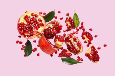 Tohumları ve yaprakları eflatun arkaplanda uçuşan taze narlar.