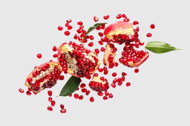 Tohumları ve yaprakları gri arkaplanda uçuşan taze narlar.