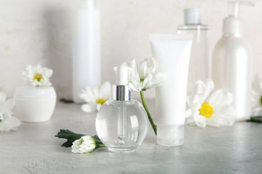 Masada farklı kozmetik ürünleri ve papatya çiçekleri