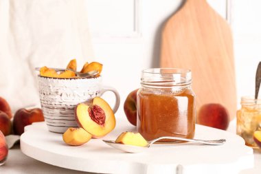Tatlı şeftali reçelli kavanoz ve masada bir fincan taze meyve