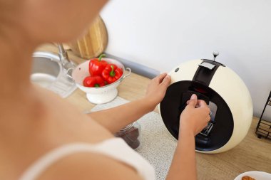 Mutfakta kahve makinesi kullanan genç bir kadın.