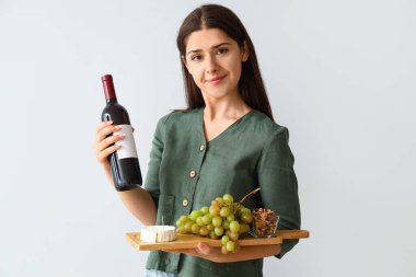 Hafif arka planda şarap şişesi olan genç bir kadın.