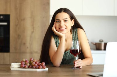 Genç bir kadın mutfakta bir bardak şarapla