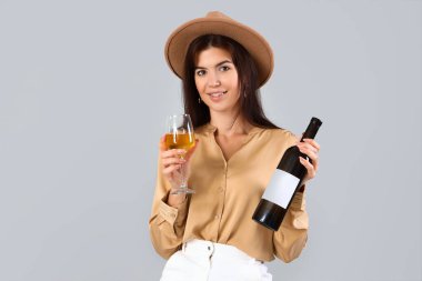 Genç ve güzel bir kadın, arka planda cam ve bir şişe şarapla