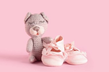 Pembe arka planda sevimli oyuncakları olan şık bebek ayakkabıları.