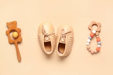 Bej arka planda çıngıraklı bebek ayakkabıları