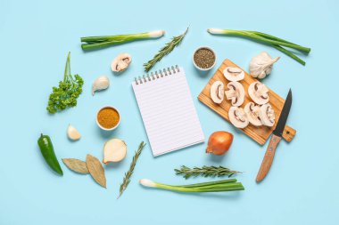 Renk arkaplanı üzerine boş tarif kitabı ve farklı malzemeler içeren kompozisyon