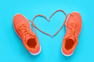 Şık spor ayakkabılar ve mavi arka plandaki bağcıklardan yapılmış kalp.