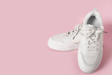 Pembe arka planda şık beyaz spor ayakkabılar