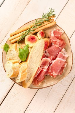 Lezzetli prosciutto, ekmek ve beyaz ahşap arka planda İtalyan Grissini dilimli tahta.