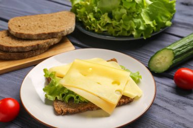 Peynirli ve marullu lezzetli sandviç. Gri ahşap arka planda, yakın plan.
