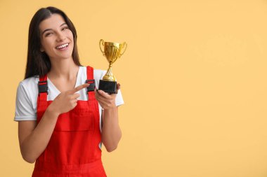 Sarı arka planda altın bardağı gösteren kadın işçi.