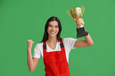 Yeşil arka planda altın bardaklı mutlu kadın işçi.