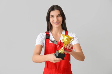 Hafif arka planda altın bardağı olan kadın işçi.