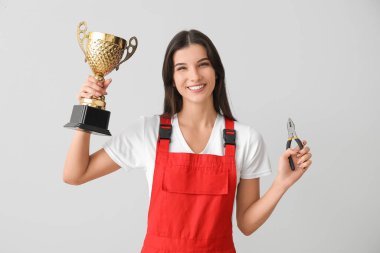 Altın bardaklı ve arka planda kerpeten olan kadın işçi.