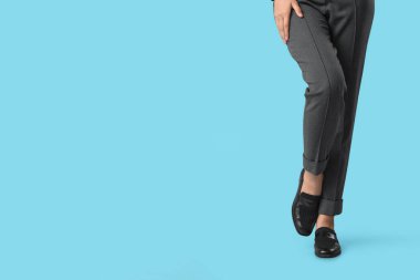 Mavi arka planda şık siyah ayakkabılı genç kadın bacakları.