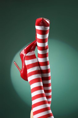 Noel çoraplı kadın bacakları ve arka planda kırmızı topuklu ayakkabılar, yakın plan.