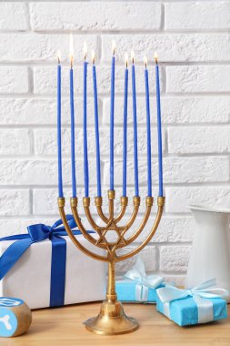 Menorah yanan mumlarla ve hediye kutularıyla ahşap masada, yakın plan. Hanuka kutlaması