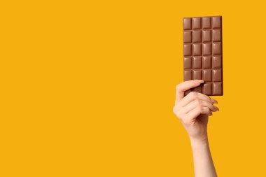 Sarı arka planda çikolatalı kadın eli.