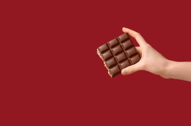 Kırmızı arka planda çikolatalı kadın eli.