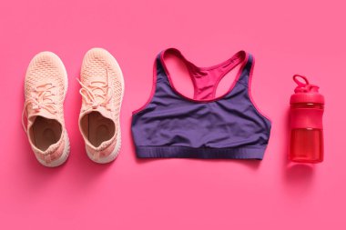 Üstü açık spor şişesi ve pembe arka planda spor ayakkabıları.