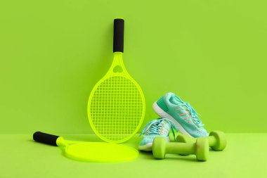 Halterli tenis raketleri ve yeşil arka planda spor ayakkabıları.
