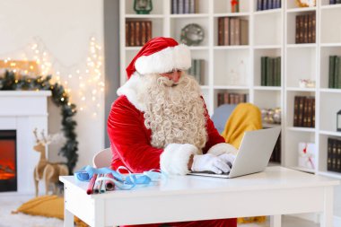 Noel Baba Noel arifesinde evde dizüstü bilgisayarla çalışıyor.