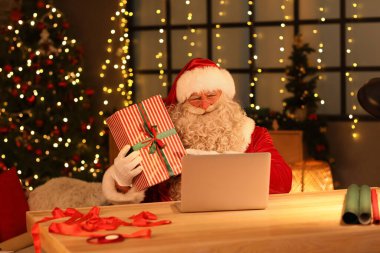 Evde dizüstü bilgisayarı ve Noel hediyesi olan Noel Baba.