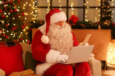 Noel arifesinde evde dizüstü bilgisayarı ve mektubu olan Noel Baba.