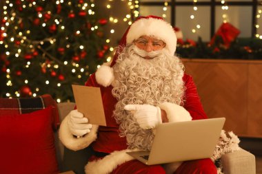 Noel için dekore edilmiş odada dizüstü bilgisayarı olan Noel Baba.