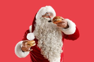 Kırmızı arka planda lezzetli burgerli Noel Baba