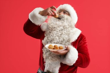 Noel Baba kırmızı arka planda lezzetli falafel topları yiyor.