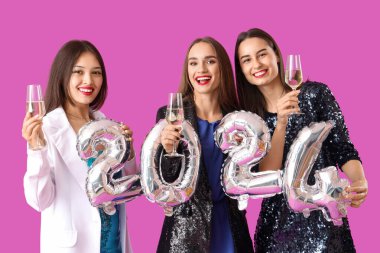 Şampanya ve 2024 model mor arka planda güzel genç kadınlar. Yeni yıl kutlaması