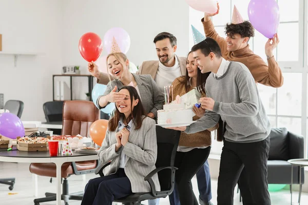 Group of business people surprising their colleague with Birthday cake at party in office