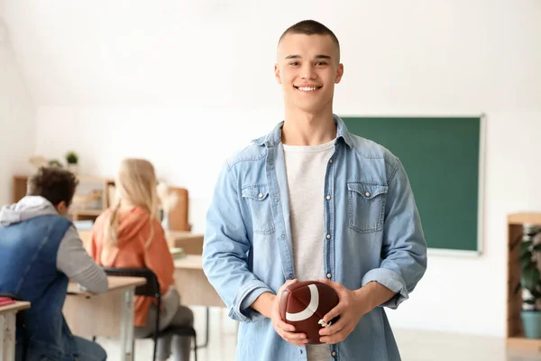 Male student with rugby ball in classroom