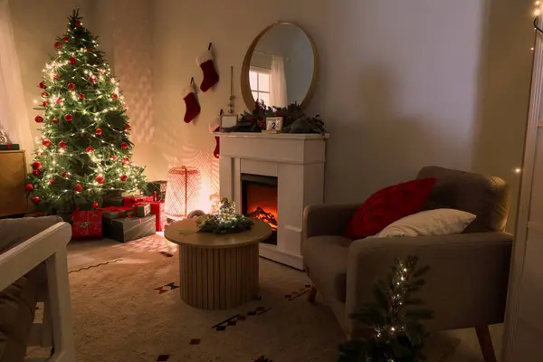 Interior of dark living room with grey armchair, fireplace, Christmas tree and glowing lights
