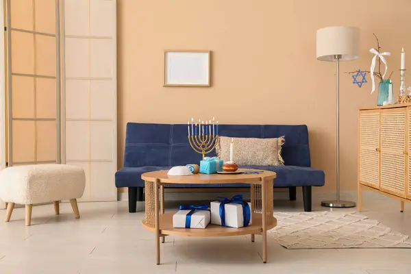 Interior of festive living room with blue sofa and decorations for Hanukkah celebration on coffee table