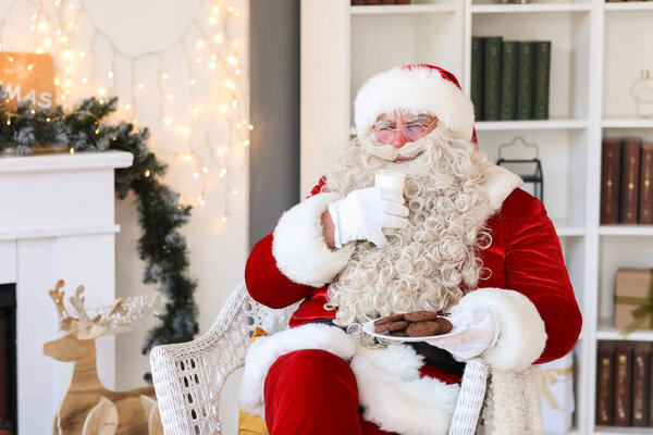 Santa Claus drinking milk with cookies at home on Christmas eve