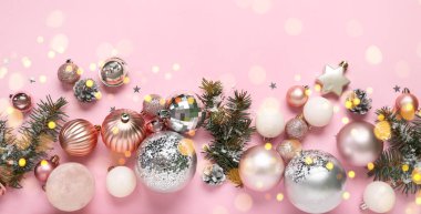 Pembe arka planda köknar dalları olan Noel baloları