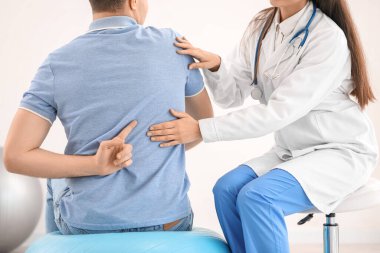 Kadın doktor klinikteki genç adamın duruşunu kontrol ediyor.