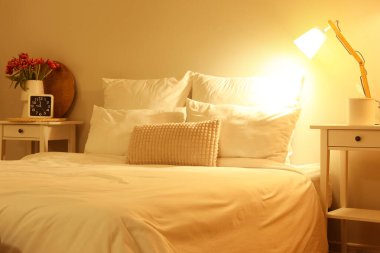 Geceleri yatak odasının içinde masalar ve parlayan lambalar.