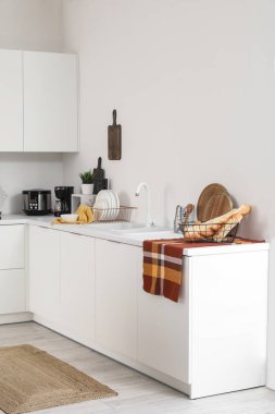 Kahve makinesi, çoklu fırın ve çatal bıçaklı beyaz mutfak tezgahları.