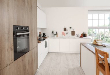 Kesme tahtaları, tahta, lavabo ve çatal bıçakları beyaz tezgahın üzerinde olan ışık mutfağının içi.